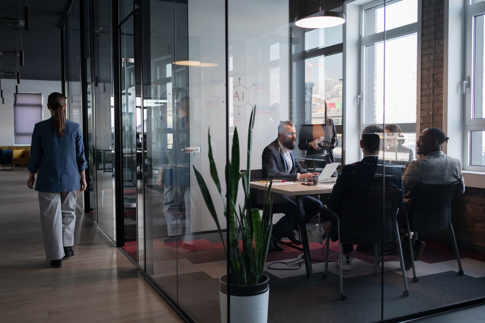 Modern office meeting in a glass-walled conference room with a diverse business team. Concept of teamwork, corporate collaboration, artificial intelligence and professional workspace environment